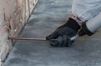 A man injecting damp proof cream into a pre-drilled hole in a building