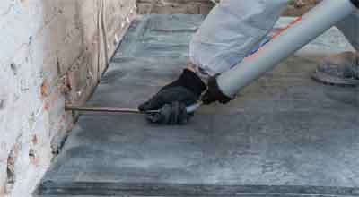 A man injecting damp proof cream into a pre-drilled hole in a building