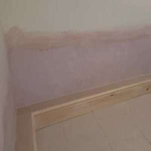 An image of a completed damp proof treatment by Grimsby Plastering Services showing a newly plastered wall with skirting board installation