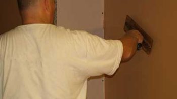 A Plasterer Plastering a studded wall holding a plastering trowel