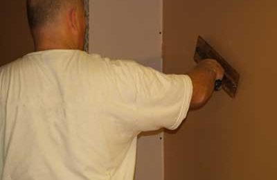 A Plasterer Plastering a studded wall holding a plastering trowel